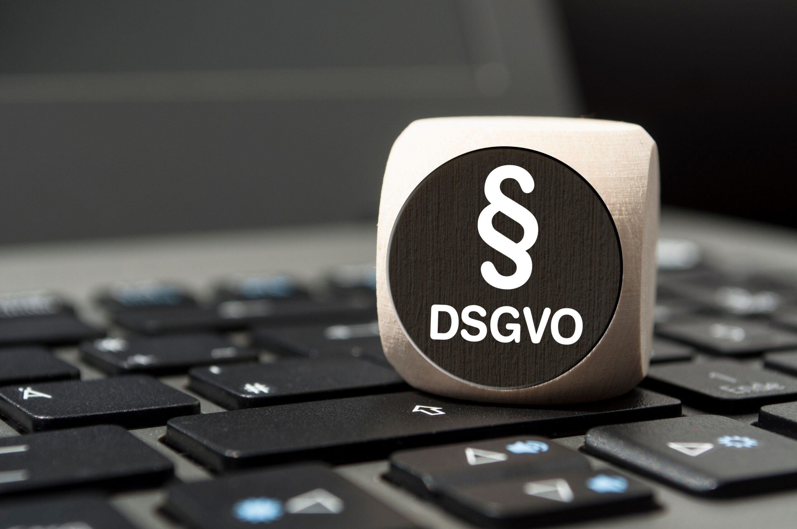 Compliance E-Learning: DSGVO-Würfel mit Paragraphenzeichen auf Tastatur als Symbol für rechtliche Wissenslücken