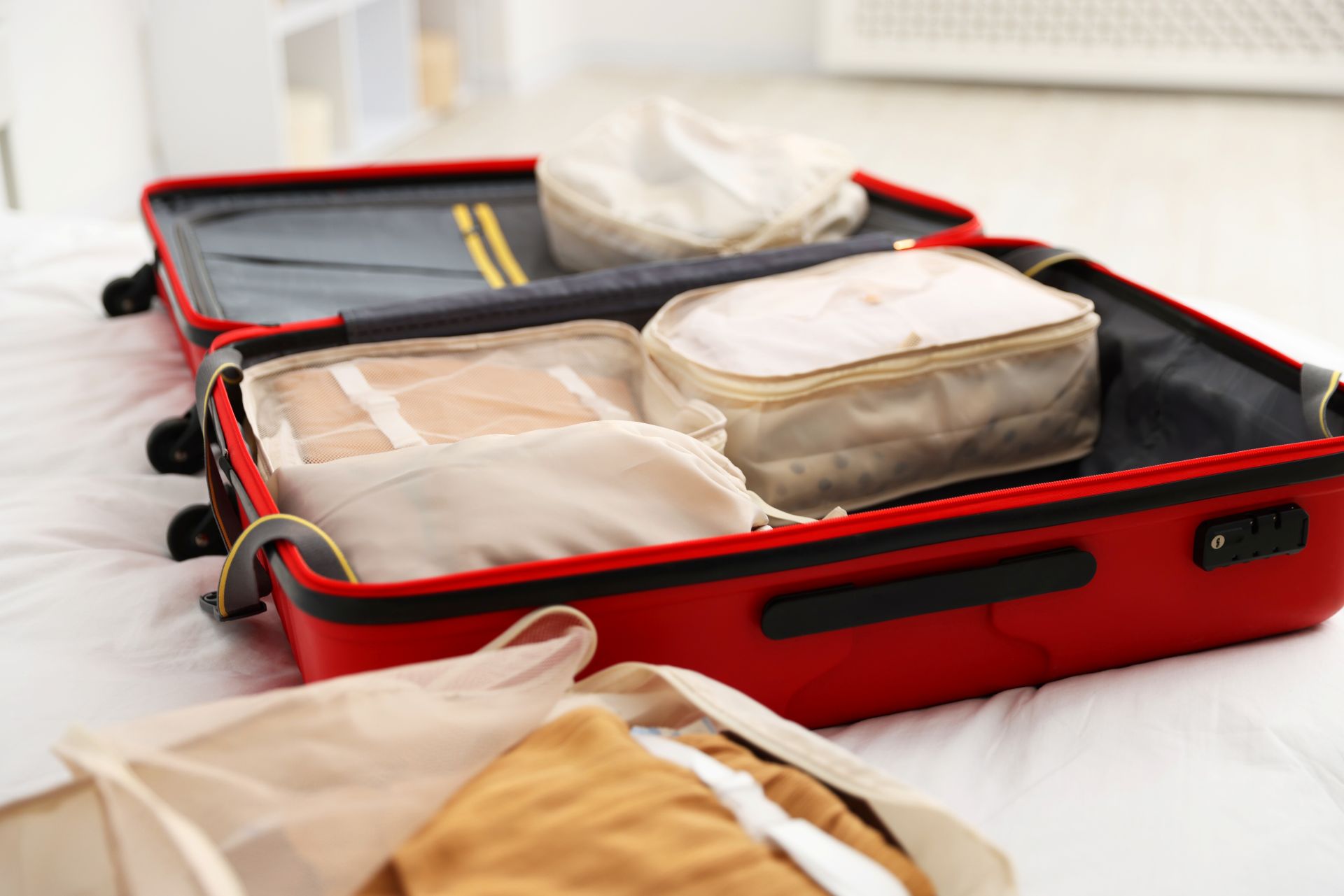 Offener Koffer mit gepackten Kleidungsstücken auf einem Bett – Reisevorbereitung