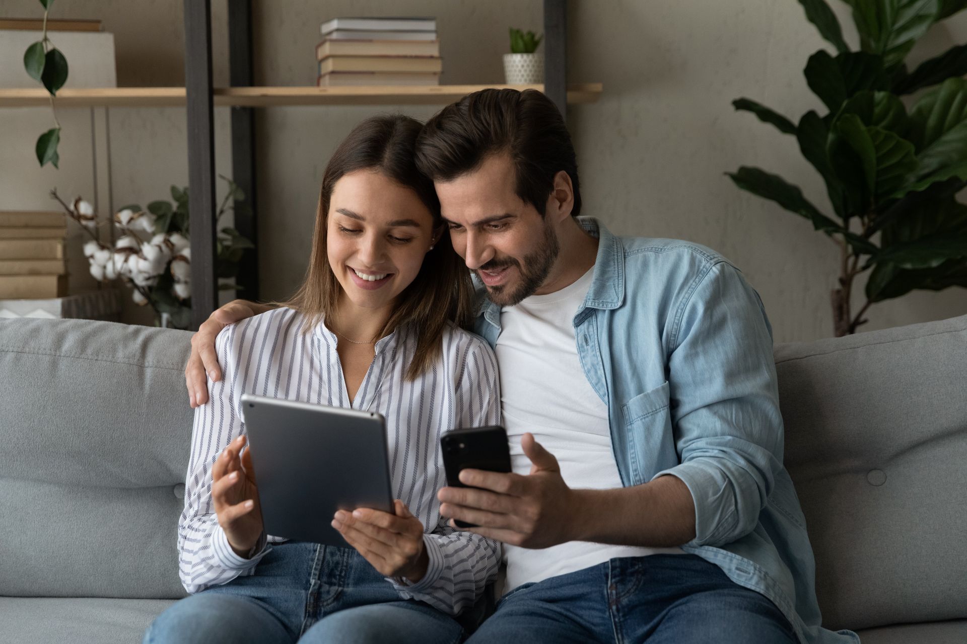 Junges Paar vergleicht Heizölpreise auf Tablet und Smartphone – modernes Verbraucherverhalten im digitalen Alltag