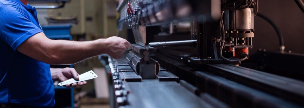 Mitarbeiter bedient Metallpresse zur Qualitaetskontrolle mit industriewaage in industrieller Fertigung