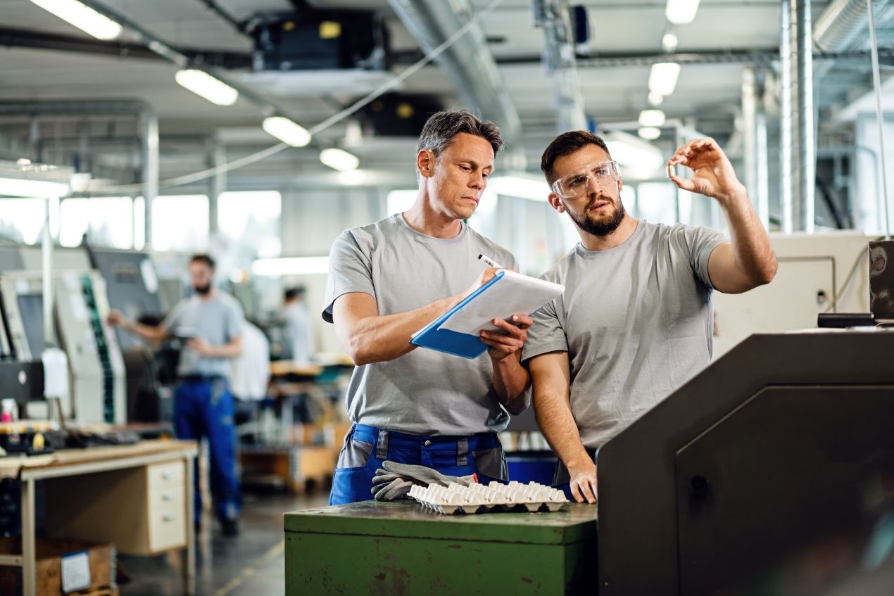 Zwei Mitarbeiter analysieren Produktqualitaet in Produktionshalle unter Einsatz einer industriewaage