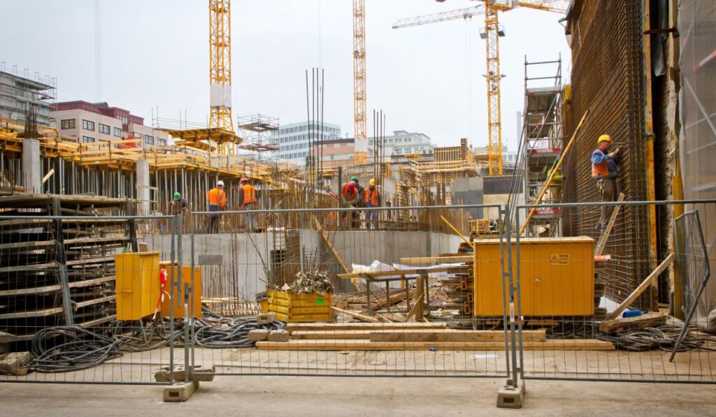 Bauzaunbanner an städtischer Großbaustelle mit Bauarbeitern, Kränen und Gerüsten zur effektiven Außenwerbung