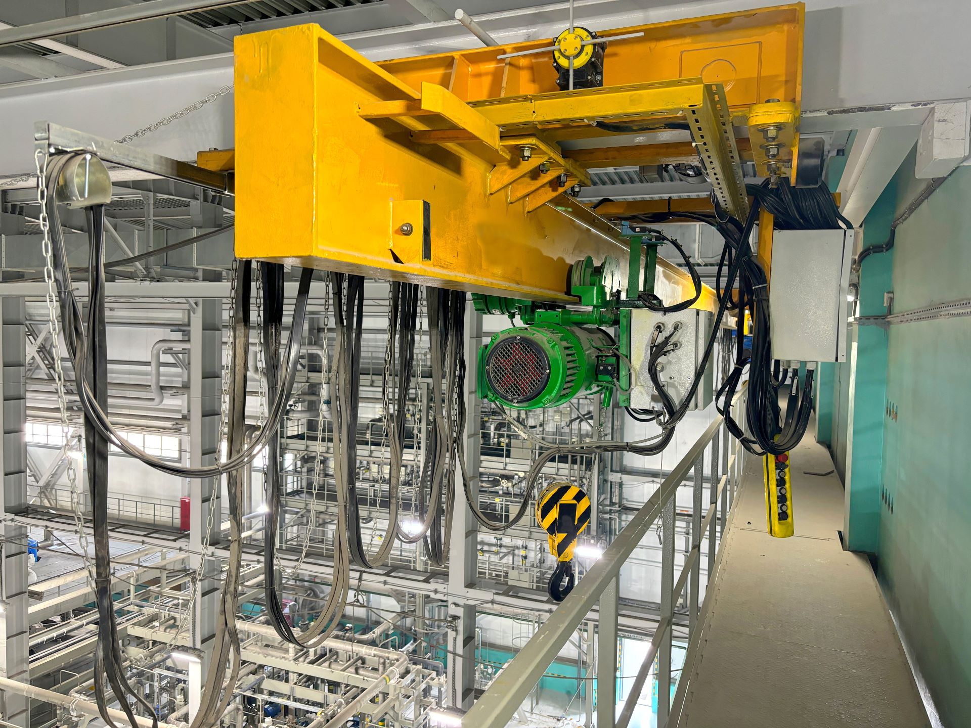 Gelber Brückenkran mit elektrischem Kettenzug in ProduktionshalleTitel (title): Elektrischer Kettenzug an gelbem Brückenkran