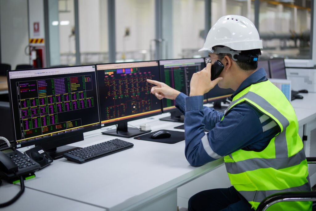Ingenieur überwacht industrielle Steuerungssysteme für elektrische Kettenzüge auf Monitoren