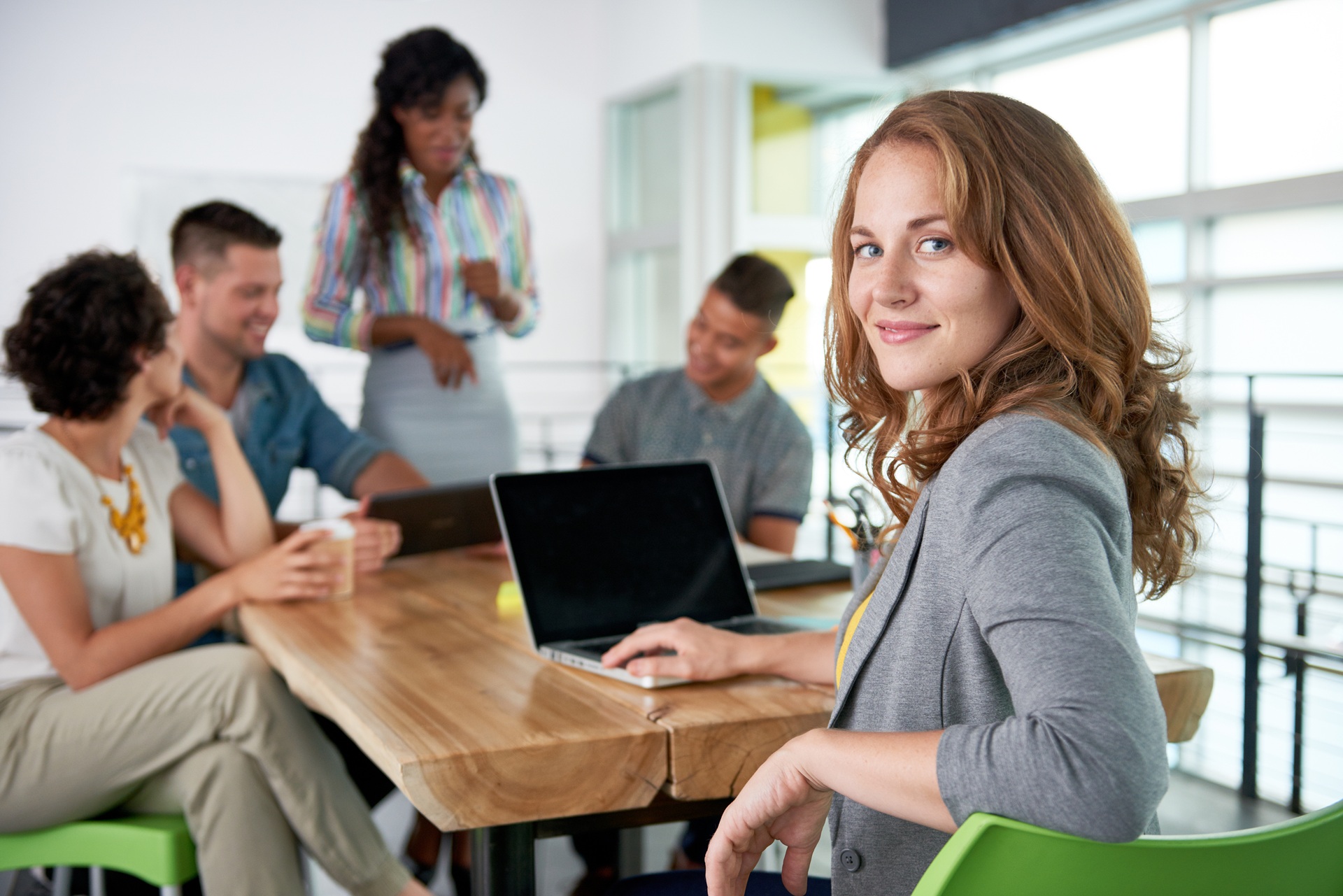 Frau sitzt im Teammeeting und blickt selbstbewusst zur Kamera | Hair Extensions