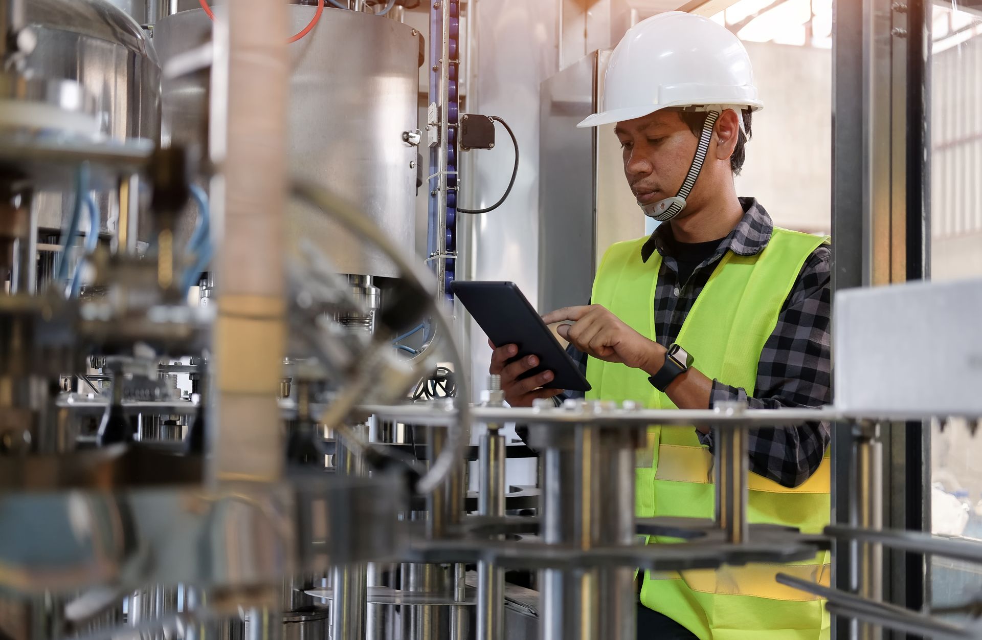 Ingenieur mit Tablet in einer Produktionsanlage prüft Messdaten eines Differenzdruckmessgeräts